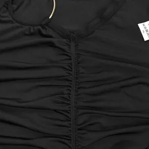 Close-up detail of black bodycon bodysuit fabric showing ruching and gold ring accent