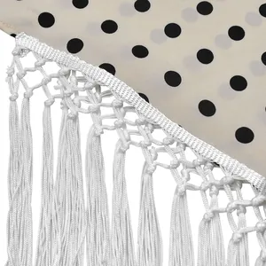 Détail macro d'un tissu à pois blancs avec une bordure de franges à glands blancs