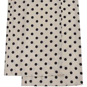 Gros plan sur un tissu léger blanc cassé avec un motif classique à pois noirs