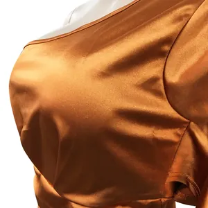 Nahaufnahme eines bronzefarbenen Satin-Kleides mit einem Träger und glatter Stoffstruktur