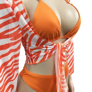 Orange bikini set with zebra print mesh cover-up detail, three-piece swimsuit on mannequin.