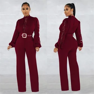Front and back detail view of a burgundy lace hollow-out jumpsuit with waist belt.