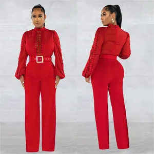 Detail view of elegant red long sleeve jumpsuit with lace hollow design and matching belt.