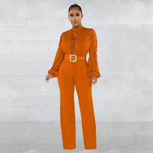 Detailed view of an orange long sleeve hollow-out lace jumpsuit featuring a belted waist.