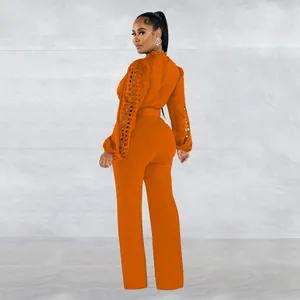 Detailed back view of an orange long-sleeve fashion jumpsuit with lace sleeves and belt.