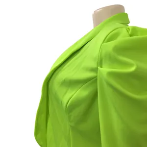 Macro view showing the intricate pleated shoulder detail on a neon green women's blazer