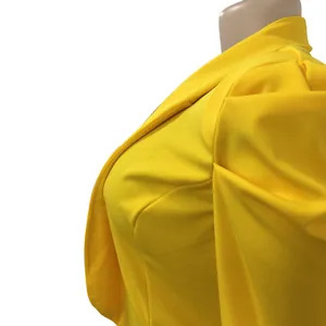 Close-up detail of bright yellow blazer featuring pleated puff shoulders and classic lapel
