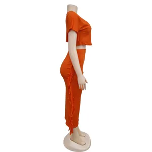 Seitenansicht des orangefarbenen Fransen-Zweiteilers mit Crop-Top und Maxirock