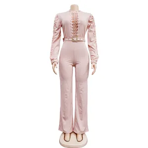 Detailed view of a pink long-sleeve jumpsuit featuring hollow lace and waist belt detail.