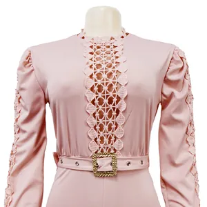 Close-up of pink jumpsuit featuring intricate lace hollow-out details and gold buckle belt