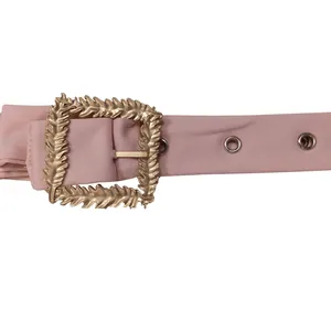 Macro detail of a stylish pink fabric belt with a large ornate golden hollowed buckle