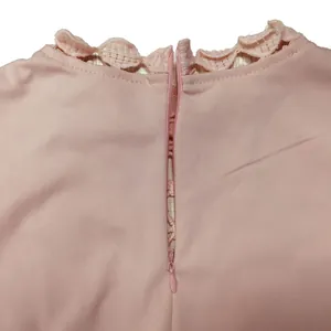 Detail view of pink jumpsuit featuring back invisible zipper and scalloped lace collar