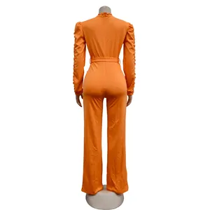 Detailed back view of an orange long-sleeve jumpsuit with lace trim and matching belt.