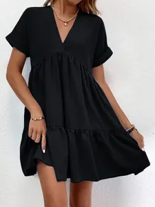 Détail de la robe noire courte à col en V montrant l'ourlet fluide à volants.