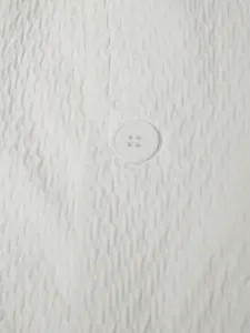 Détail en gros plan de la texture du tissu seersucker blanc avec un bouton classique