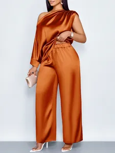 Satijnen set met een elegante one-shoulder top en wijde pijpen in een warme oranje kleur