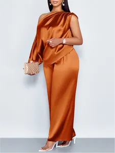 Elegant oranje satijnen tweedelig pak met top met schuine schouder en wijde broek