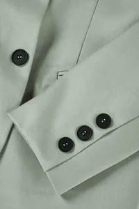 Detailansicht der hellgrünen Business-Blazer-Manschette mit drei schwarzen Knöpfen und Stoffstruktur