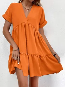 Détail d'une robe courte orange vif à col en V avec une jupe à plusieurs niveaux