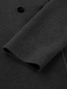 Close-up detail of dark grey wool coat sleeve showing fine fabric texture and button