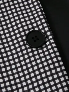 Détail en gros plan du motif vichy noir et blanc avec un bouton noir sur le costume