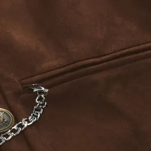 Close-up detail of brown suede vest showing pocket, metal chain and vintage button