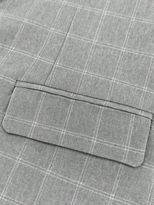 Close-up of grey checkered fabric and pocket flap detail on a men's business suit