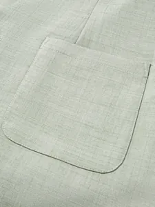 Vue détaillée d'une poche poitrine en lin vert sauge sur une veste de costume pour homme.