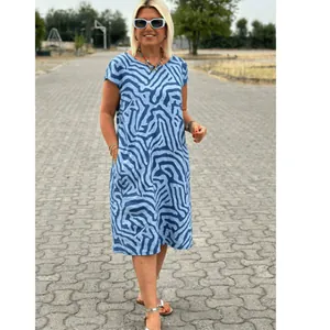 Detail of woman wearing blue Bohemian abstract print midi dress in outdoor resort setting.