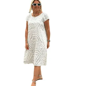 Woman in a bohemian leopard print dress and white sunglasses on a plain background