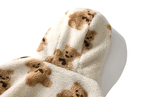 Dettaglio ravvicinato di felpa con cappuccio in peluche bianca con motivo a orsetto