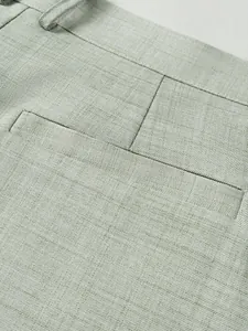 Gros plan d'un pantalon de costume vert sauge montrant la poche et la texture du tissu.