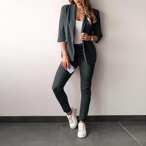 Full-length view of a woman in a chic charcoal grey blazer and trouser suit set.