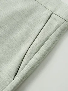 Gros plan détaillé du tissu texturé vert clair et de la poche latérale d'un pantalon de costume