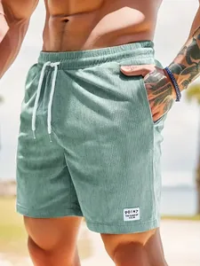Detailansicht der grünen Cord-Herrenshorts mit Kordelzug und Zieraufnäher.