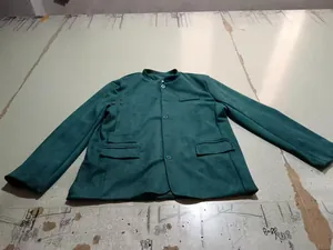 Detailed macro view of a vintage deep green men's suede workwear jacket laid flat