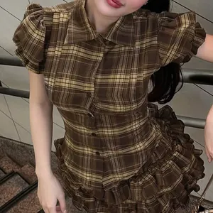 Detail view of a vintage brown plaid shirt featuring puff sleeves and ruffle tiered skirt.