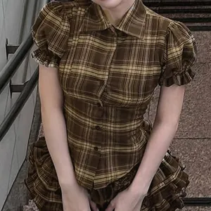 Vintage brown plaid button-up shirt featuring puff sleeves and ruffled hem, retro school style.