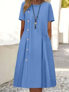 Détail d'une robe midi bleue à manches courtes avec boutons décoratifs et poches latérales