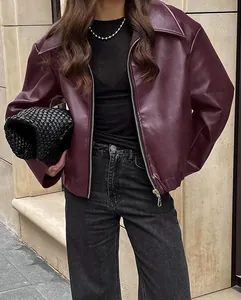 Detailopname van een bordeauxrode oversized leren jas met een getextureerde afwerking