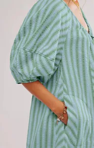 Detail of a green striped summer jumpsuit showing the lantern sleeve and side pocket