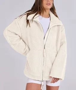 Detail view of woman's oversized cream sherpa jacket featuring double zipper and soft texture