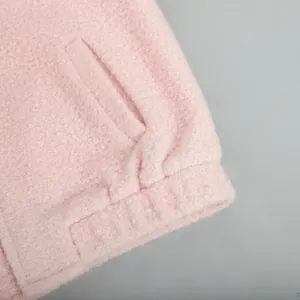 Macro detail of a soft pink fuzzy fleece jacket showing material texture and pocket