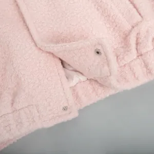 Detailed macro view of pink sherpa fleece jacket fabric and metal snap button closure