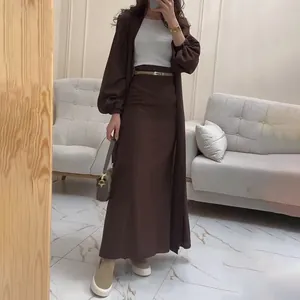Vue en pied d'une femme portant un ensemble deux pièces jupe longue et cardigan brun