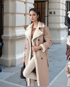 Elegante cappotto lungo da donna in shearling beige con collo a revers indossato da modella