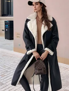 Modella che indossa un lungo cappotto nero in montone sintetico con fodera in pile bianco