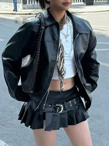 Détail d'un blouson moto noir en similicuir avec une mini-jupe plissée assortie tendance.