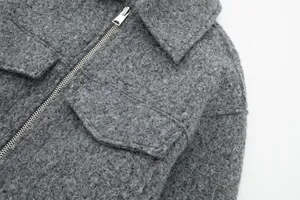 Detaillierte Makroansicht einer grauen Tweedjacke mit Reißverschluss und Stoffstruktur.
