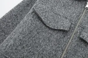 Nahaufnahme der grauen Bouclé-Stofftextur und des Reißverschlusses der Tweedjacke.